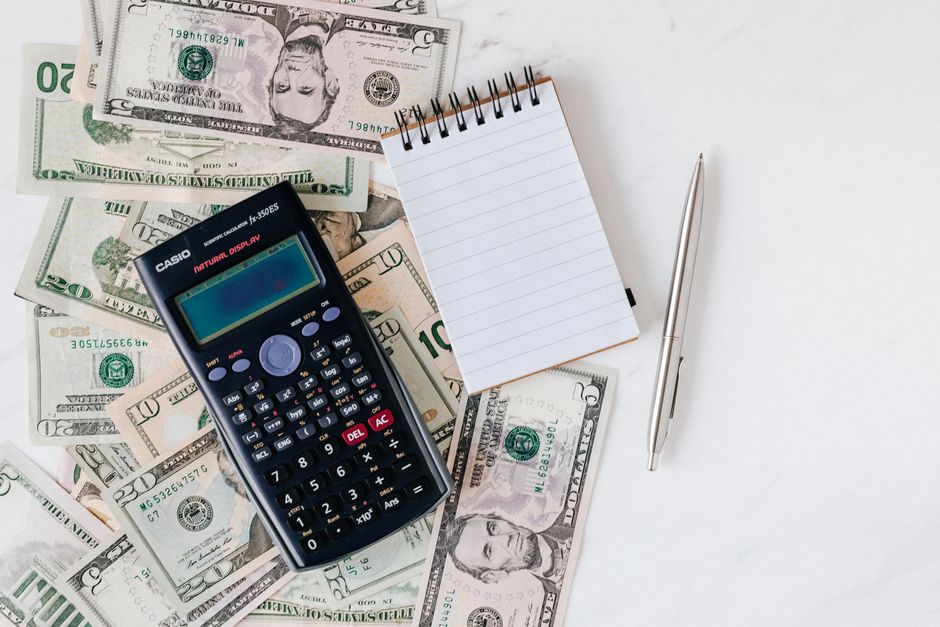 Top view of electronic calculator and notepad placed over United States dollar cash money together with metallic pen for budget planning and calculation